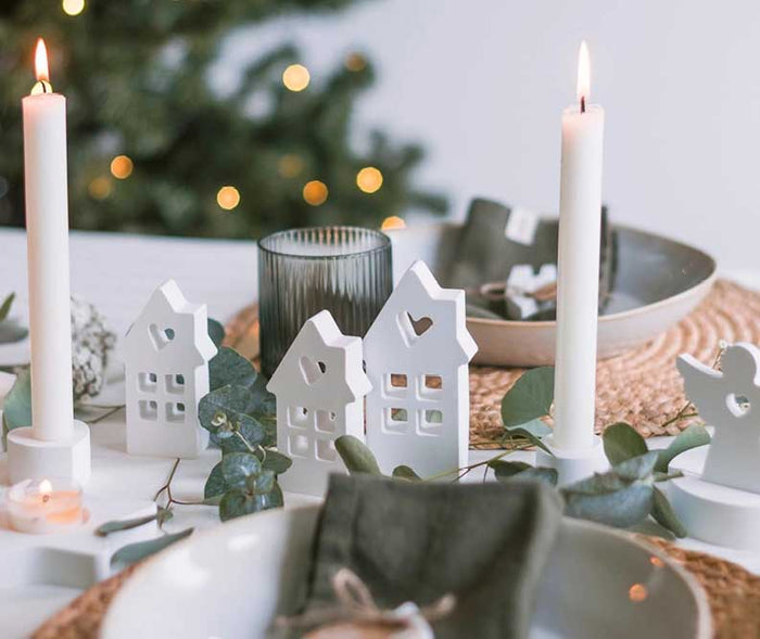 Festlich gedeckter Weihnachtstisch mit selbst gegossenen Deko-Häuschen, Kerzenhaltern und Engeln als stilvolle DIY-Weihnachtsdekoration.