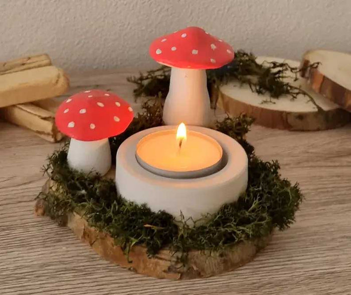 Selbst modellierte Pilze mit roten Kappen und weissen Punkten umrahmen ein Teelicht und schaffen eine gemütliche, herbstliche Tischdekoration.
