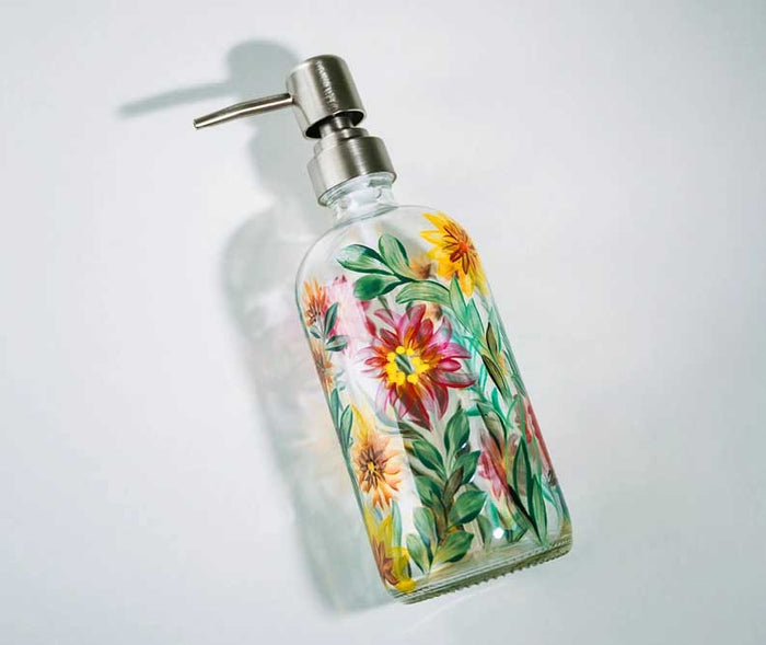 Ein selbst bemalter Glas-Seifenspender mit farbenfrohen Blumenmotiven setzt als stilvolle DIY-Dekoration einen besonderen Akzent im Badezimmer.