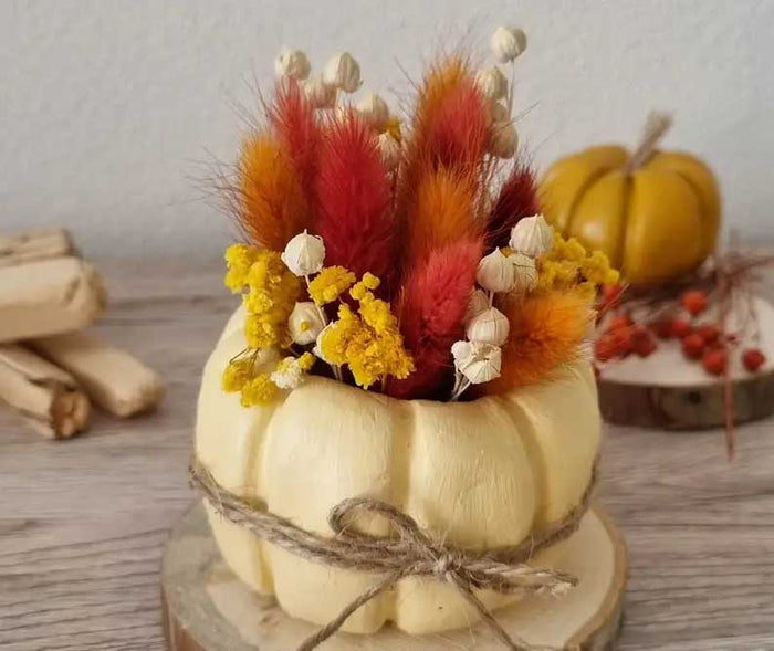 Selbst gestalteter Deko-Kürbis dient als Vase für Trockenblumen und bringt natürliche Herbstfarben in eine stilvolle Tischdekoration.