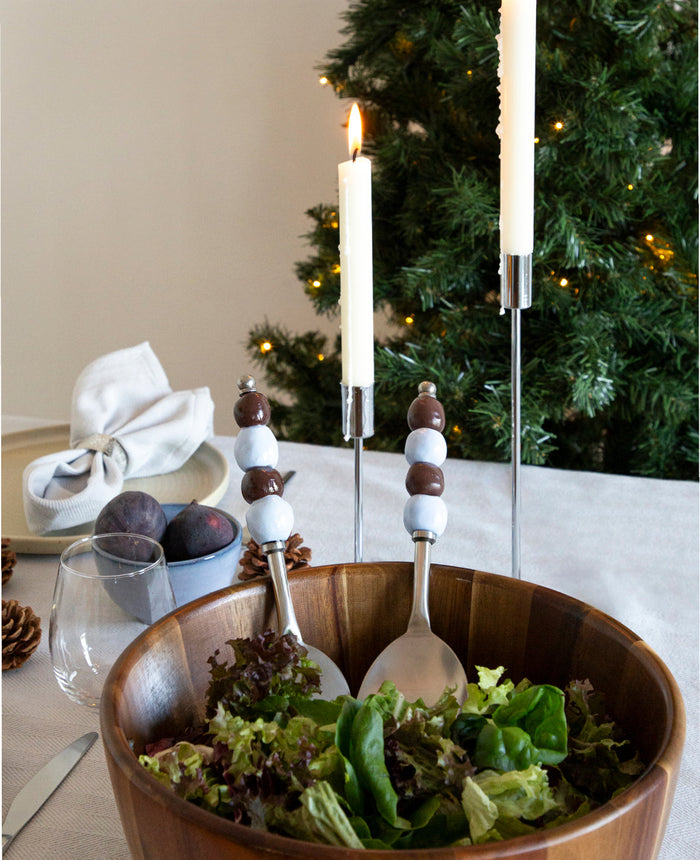 Salatbesteck mit braunen und hellblauen Perlengriffen in Akazienholzschüssel mit Salat, weihnachtlicher Tisch mit Kerzen und Tannenbaum