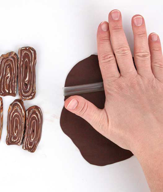 Hand rollt braune FIMO Modelliermasse mit einem Acrylroller aus, daneben Stücke mit Holzoptik in Braun und Beige