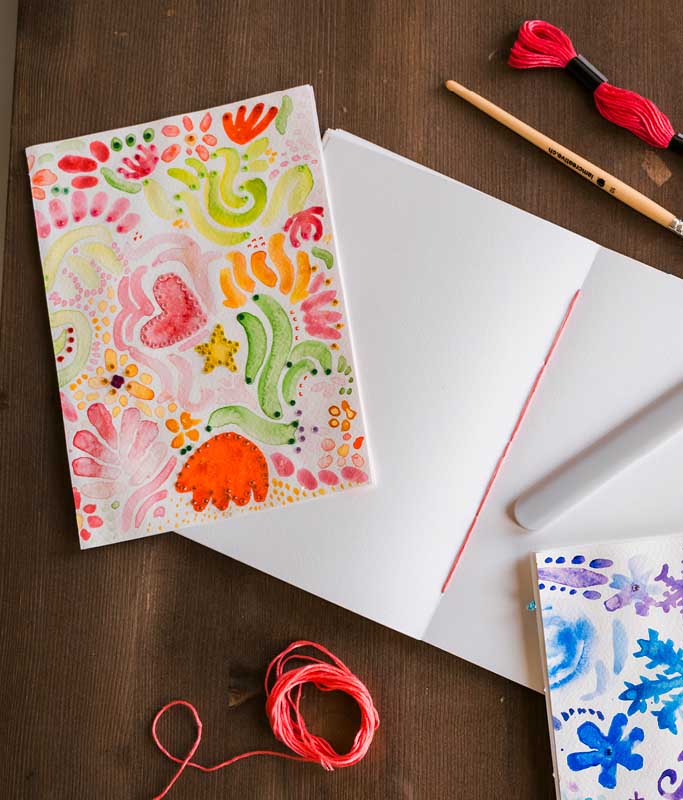 Selbst gestaltetes Aquarell-Notizheft mit Stickgarn und kreativen Wintermotiven