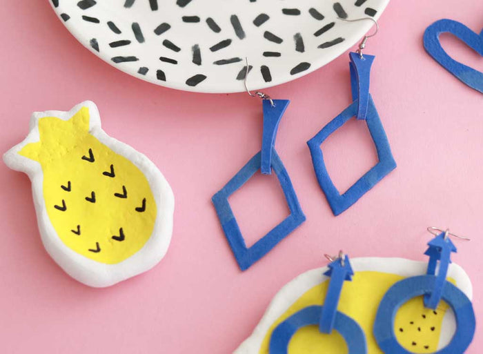 Herzförmiger blauer Ohrring aus FIMO mit silbernem Ohrhaken auf pinkem Hintergrund
