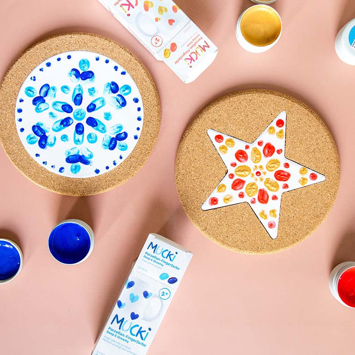 Kreatives Gestalten mit MUCKI Fingerfarben – bunte Fingerabdrücke auf einem Keramikteller und einem Stern, kreative Bastelideen für Kinder.