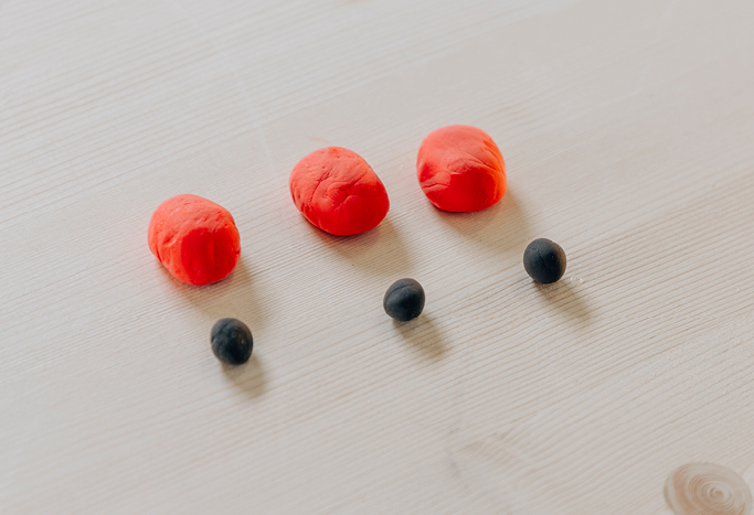 7. Forme aus dem roten Silk Clay drei runde, leicht flache Kugeln. Zusätzlich drei kleine schwarze Kugeln für die Köpfchen der Marienkäfer.