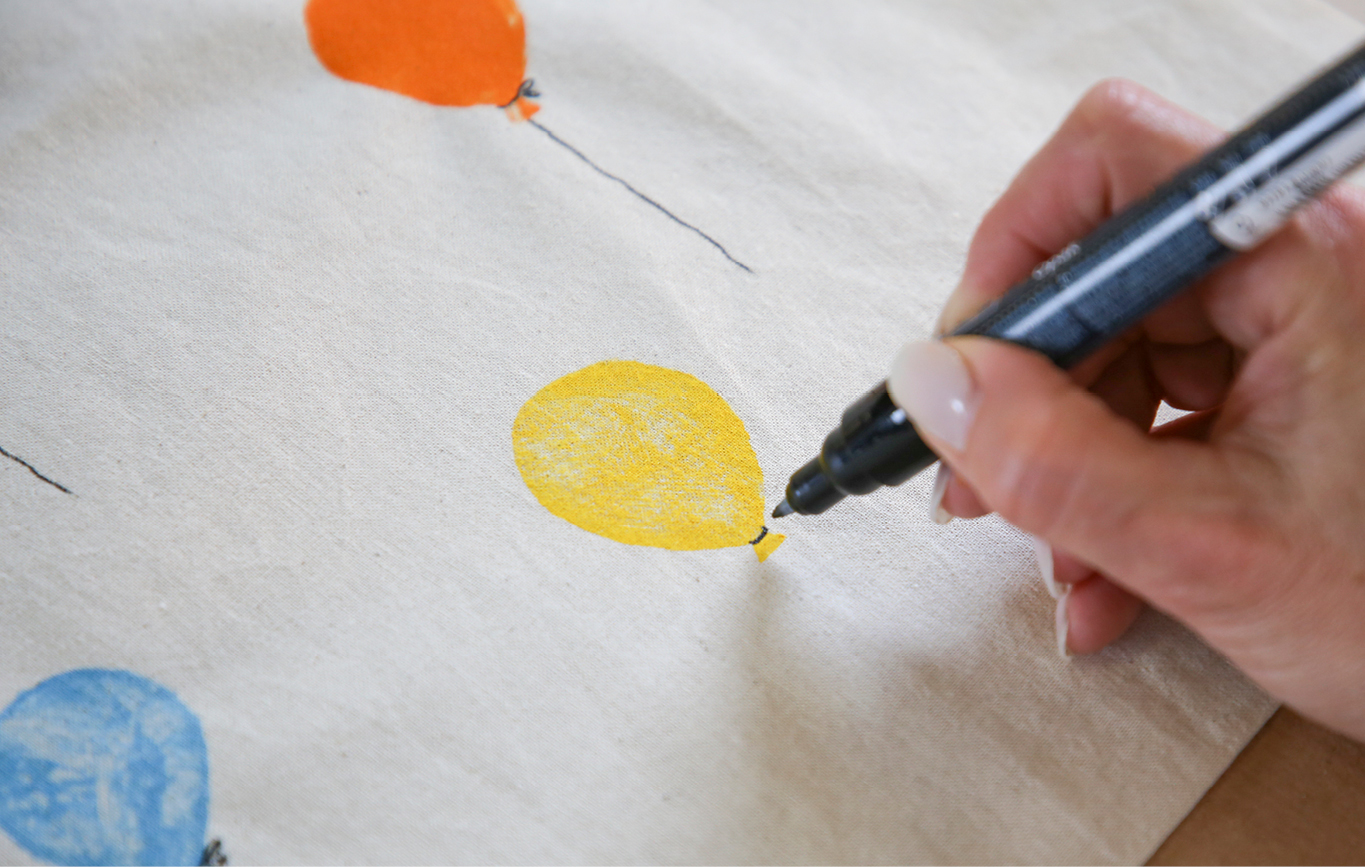 6. Sobald die Farbe eingetrocknet ist, wird die Ballonschnur mit dem Textilmarker aufgezeichnet. Zum Fixieren der Farbe, die Tasche für 8 Minuten bei 150° in den Ofen schieben.