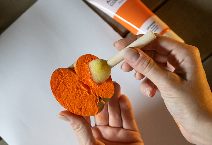 2. Bestreiche den Apfel mit Hilfe eines Schwammstempels mit orangefarbener Farbe.